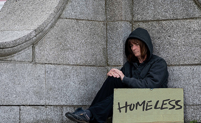 homeless person sitting with sign